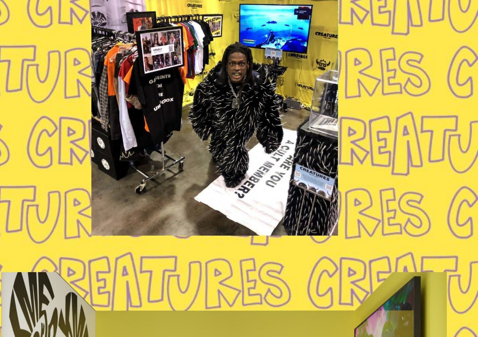 BillyRacxx in the CREATURES suit at the DesignerCon booth, surrounded by tees and merch